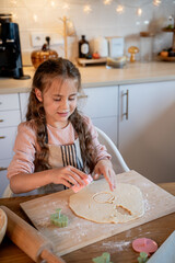 Little cute girl baking cookies in the kitchen. Homemade pastries. Cozy autumn.