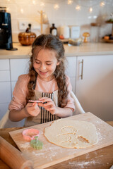 Little cute girl baking cookies in the kitchen. Homemade pastries. Cozy autumn.