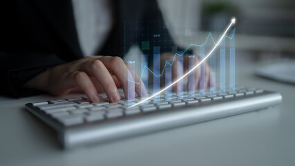 A close-up of hands on a keyboard with a digital graph overlay showcasing upward trends, symbolizing growth and success in the business and finance sectors. Impute