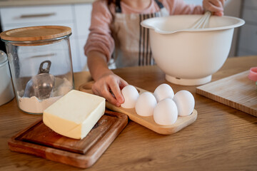 Little cute girl is beating eggs in the kitchen. Homemade baking. Cozy autumn.