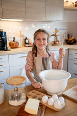 Little cute girl is beating eggs in the kitchen. Homemade baking. Cozy autumn.