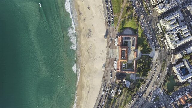 Drone video from high above bondi beach looking directly down at Bondi Pavilion in a still shot showing slow movements of the coastline