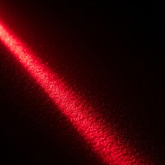 Red light beam on dark textured surface, creating a dramatic effect.
