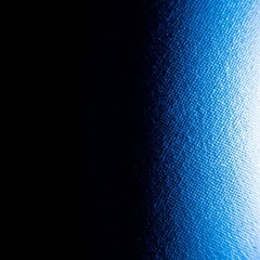 Close-up abstract texture of a dark blue fabric with a bright light illuminating the right side, creating a gradient effect.