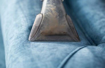 Cleaning process using a steam cleaner on a blue upholstered couch in a cozy living room