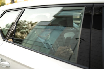 Senior businessman using smartphone in back seat of car
