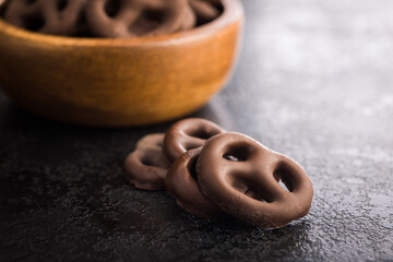 Chocolate covered pretzels on black table.