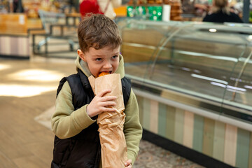 Little boy eating a freshly baked baguette bought from a bakery. High quality photo. Bread and breakfast concept,