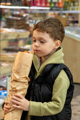 Little boy eating a freshly baked baguette bought from a bakery. High quality photo. Bread and breakfast concept,