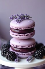 Purple macarons stacked with fresh blackberries and lavender sprigs. Delicate French pastry treat with rich blackberry filling. Perfect sweet dessert for any occasion.
