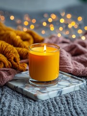 A cozy candlelit scene featuring a warm yellow candle on a marble tile, surrounded by textured fabrics in shades of orange and brown, set against a blurred background with soft lighting that