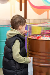 A little boy chooses gummies at a candy store. Unhealthy food for kids. Unhealthy snack. High quality photo