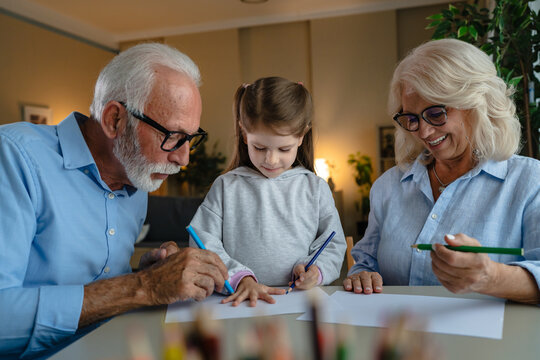 Grandparents and granddaughter drawing, learning, creating at home