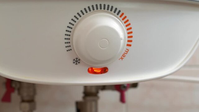 Boiler with temperature regulator of heating cold water. Boiler heats water from cold water supply system. Red light indicator comes on - boiler works to heat the water. Zoom-in video