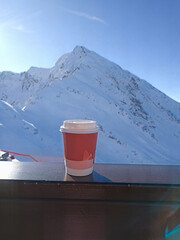 A red cup with a white lid sits on a wooden railing