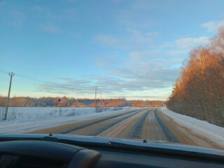 A car is driving down a snowy road.