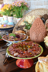 gourmet charcuterie platter close up, prosciutto ham and pickled vegetables antipasto, luxurious fine dining buffet setup, decorated table centerpiece and food

