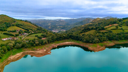 Obraz premium Countryside lake with farmland and mountains in Asturias