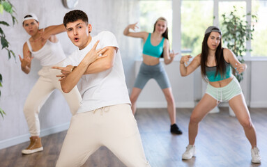 Active teenagers dancing modern dances in a modern studio