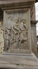 Rome, Italy - 13 January 2025. Four robed male figures in high relief are carved into a stone panel on the Arch of Septimius Severus, appearing in a close, engaged conversation.