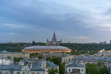 Naklejka premium A stunning scene captures a large sports stadium and an iconic building in Moscow as the sky transitions into twilight, creating a beautiful backdrop against city architecture.