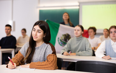Young female student attentively listening to a lecture in a classroom