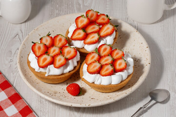 Delicious strawberry tarts topped with fresh berries served on a cream-colored plate in a cozy kitchen setting
