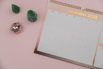 Open calendar page December 2025 and Christmas decorations on pastel pink background. Top view