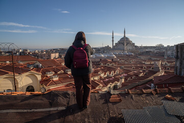 Istanbul Turkey Earthquake Aftermath: Woman surveys damaged rooftops, Suleymaniye Mosque background.