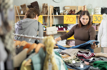 Adult and young women buyers choosing winter clothes in clothing store