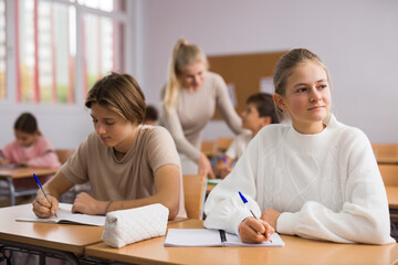 Portrait of teenage school girl and boy sitting together in classroom during lesson in secondary school