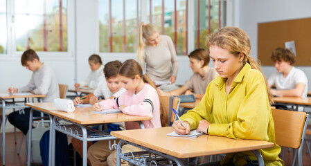 Young boys and girls studying in classroom during lesson in school.