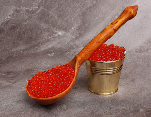 a spoon and a bucket of red caviar