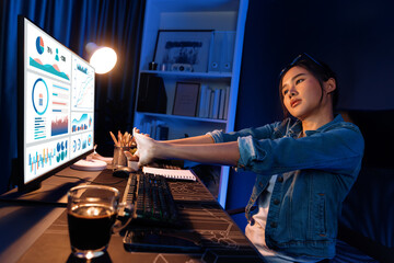Young beautiful Asian businesswoman taking break with stretching body with ache symptom for relaxing muscle after finishing overworked load report at neon light modern office at night time. Stratagem.