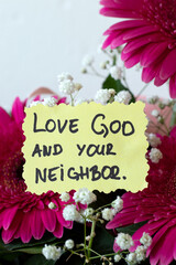 Love God and your neighbor, inspirational Christian quote on paper with flowers. Obedience to Jesus Christ, spiritual growth, biblical concept.