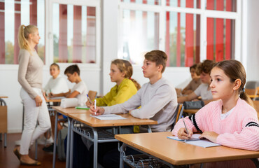 Teenage students are sitting at their desks in classroom