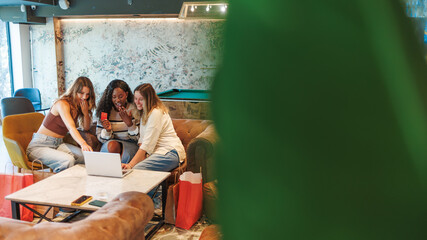 Group of excited diverse young women buying products online with a laptop and credit card