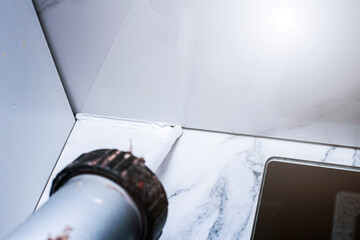 applying sealant to the gap between porcelain tiles to prevent debris from getting in and unsanitary conditions