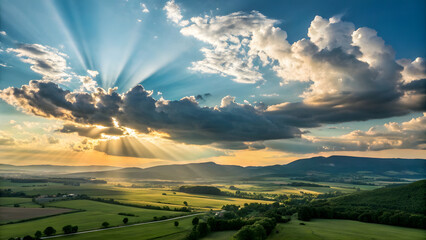 Fototapeta premium Brilliant midday sunlight bursts through a dynamic sky filled with soft, billowing cumulus clouds, creating a dramatic interplay of light and shadow across the landscape below.