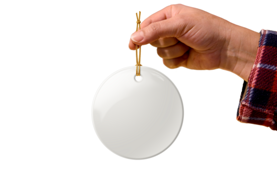 Hand holding Christmas round ceramic ornament or decoration with golden string mockup isolated on a transparent background, PNG. High resolution. Mockup, template ready for your design.