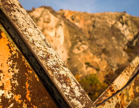 Rusty metal beams against a backdrop of hills - Powered by Adobe