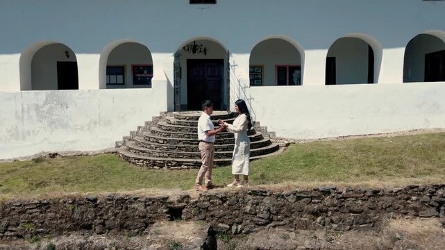 Abrazo tierno de pareja enamorada en vestidos blancos, retrato panor&aacute;mico rural. pareja vestida de blanco frente a una casona panor&aacute;mica.estilo de vida