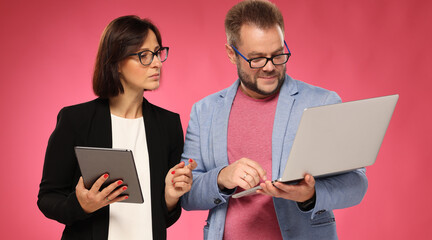 Businesswoman and businessman using electronic devices on pink background