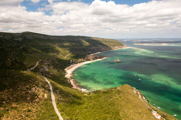 Fototapeta premium Scenic aerial shot of Praia de Alpertucho beach, located in beautiful Arrabida National Park, Portugal, surrounded by lush green hills and clear turquoise waters