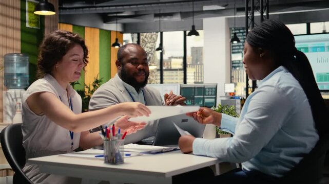 Diverse hiring team and black candidate discuss about qualifications for a job opening within the business organization. Evaluating CV resume information, head hunting concept. Camera A.