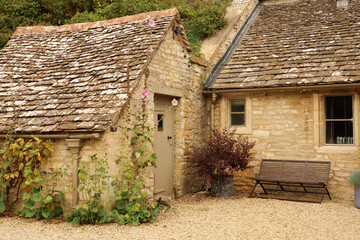 Rustic Cotswold stone cottage exterior with weathered slate roof, traditional architecture and quaint garden details