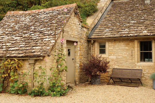 Rustic Cotswold stone cottage exterior with weathered slate roof, traditional architecture and quaint garden details