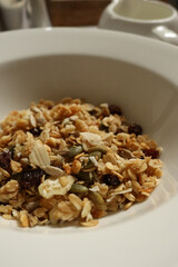 Granola mix with oats, seeds, and dried fruit in a white bowl. Cotswolds countryside, England