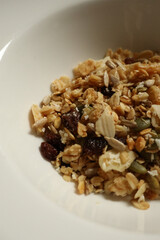 Granola cereal mix filling white bowl, featuring healthy breakfast ingredients. Cotswolds countryside, England