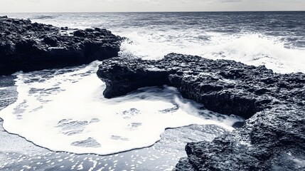 Ocean waves crashing against the rocky shore in monochrome tones creating dramatic landscape